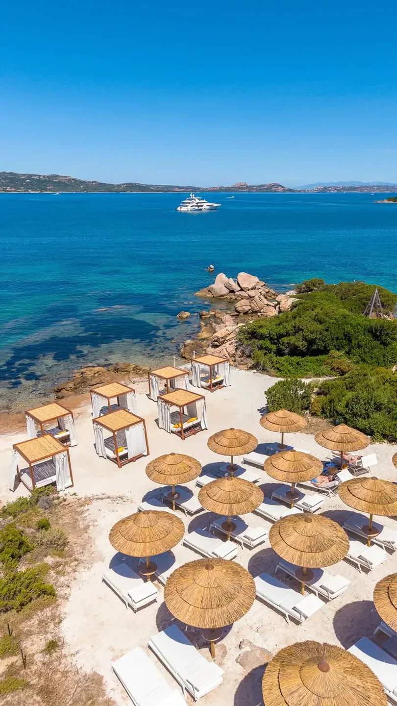 Cone Club beach club in Sardinia with luxury cabanas and sun loungers on a white sandy beach overlooking the turquoise sea.